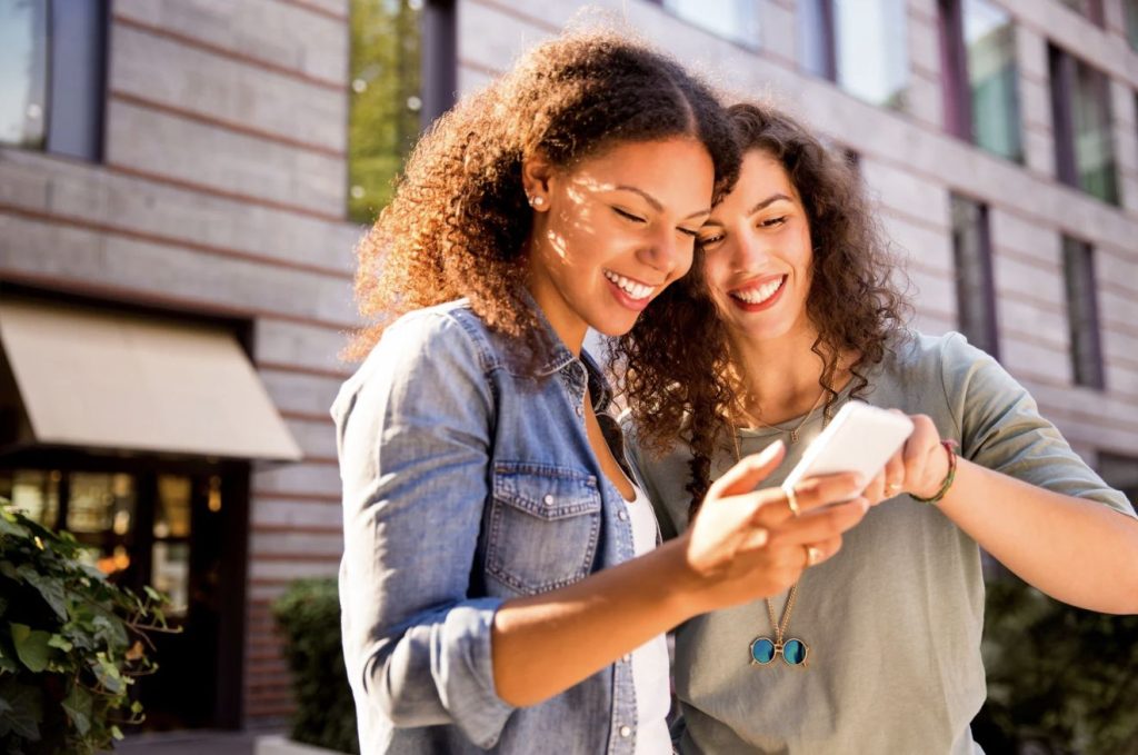 Two smiling women looking at a phone together